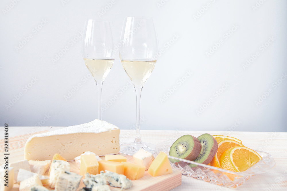 white wine two glasses and cheese on a wooden board