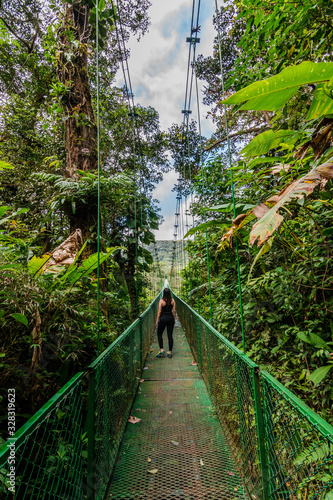 Woman walking in a  suspension bridge during vacations in the forest