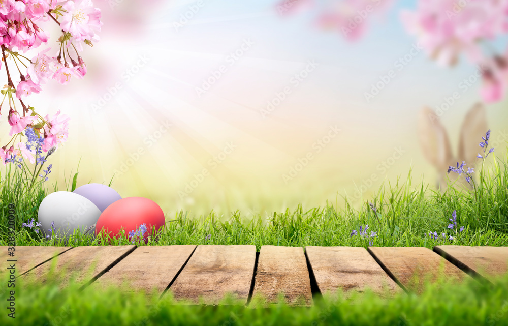 A wooden product display top with an Easter background of painted eggs, rabbit ears, green grass, meadows and pink cherry blossom flowers.