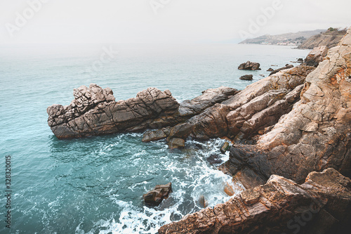 Blue waves at the rocky sea shore. Panoramic image