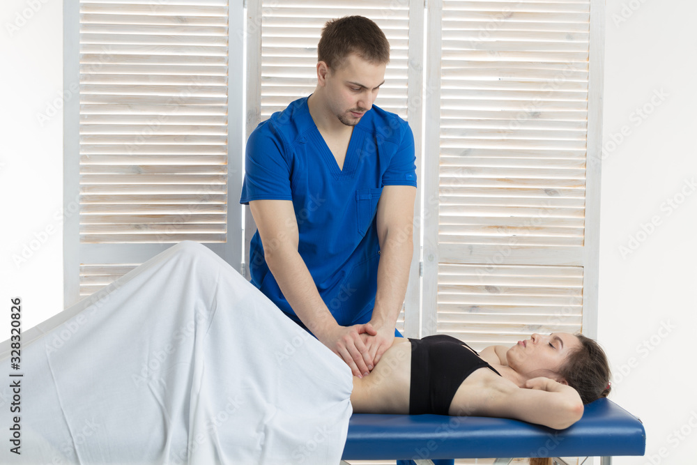 Obraz premium The doctor does diagnostics of muscles of an abdominal cavity of the patient. Removal of tension of muscles of a stomach. Stomach muscles in a tone