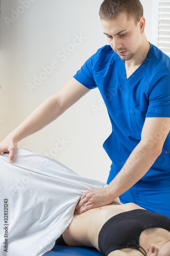 The doctor does diagnostics of muscles of an abdominal cavity of the patient. Removal of tension of muscles of a stomach. Stomach muscles in a tone