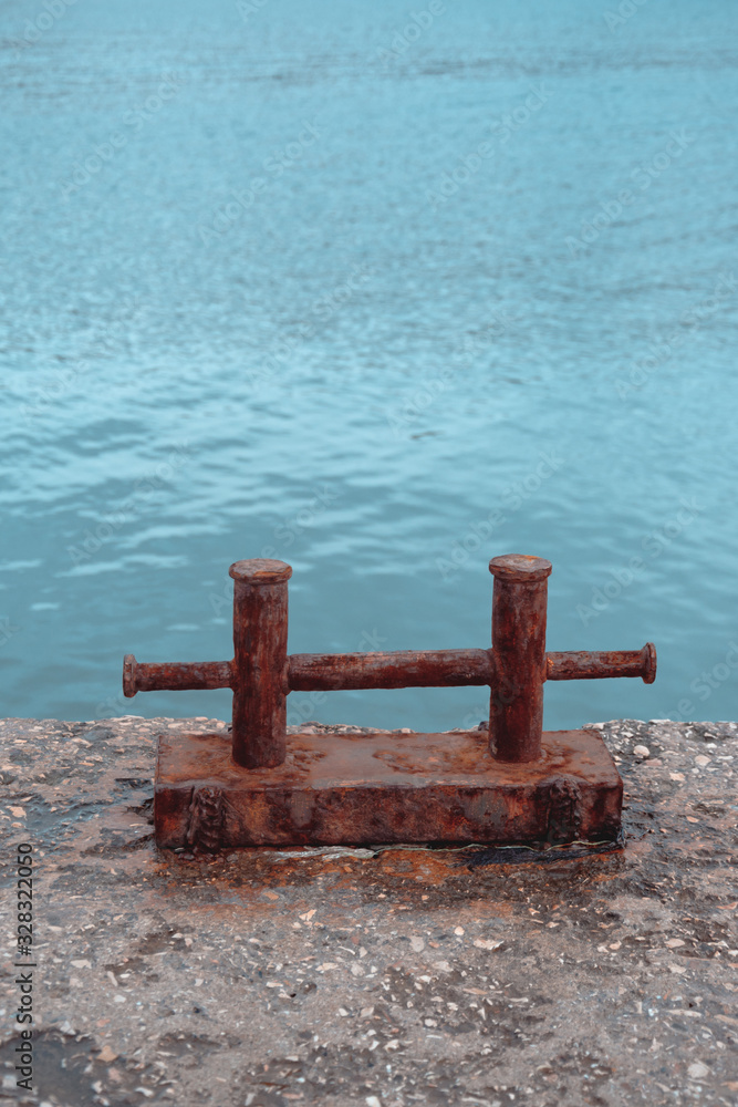 Fototapeta premium Rusty steel double berth on a fragment of an old concrete pier against a background of turquoise sea water