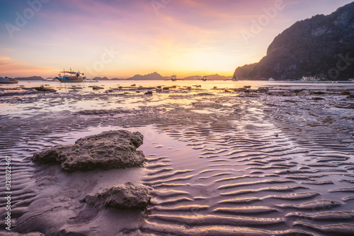 Corong beach  El Nido  Philippines. Sunset on tropical beach. Sun reflections at the golden hour. mountain chain islands at horizon