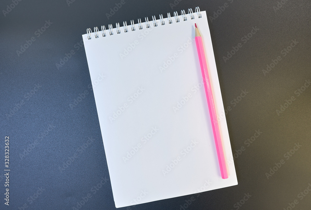 Pink pencil on a white sheet of notepad paper on a dark gradient from brown to blue background. Blank paper sheet and pencil for mock up. copy space. flat lay Pink pencil on a white sheet of notepad paper on a dark gradient from brown to blue background. Blank paper sheet and pencil for mock up. copy space. flat lay