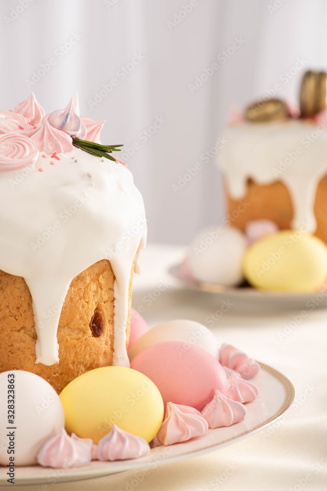 Selective focus of delicious Easter cakes with meringue and colorful eggs on plates Selective focus of delicious Easter cakes with meringue and colorful eggs on plates