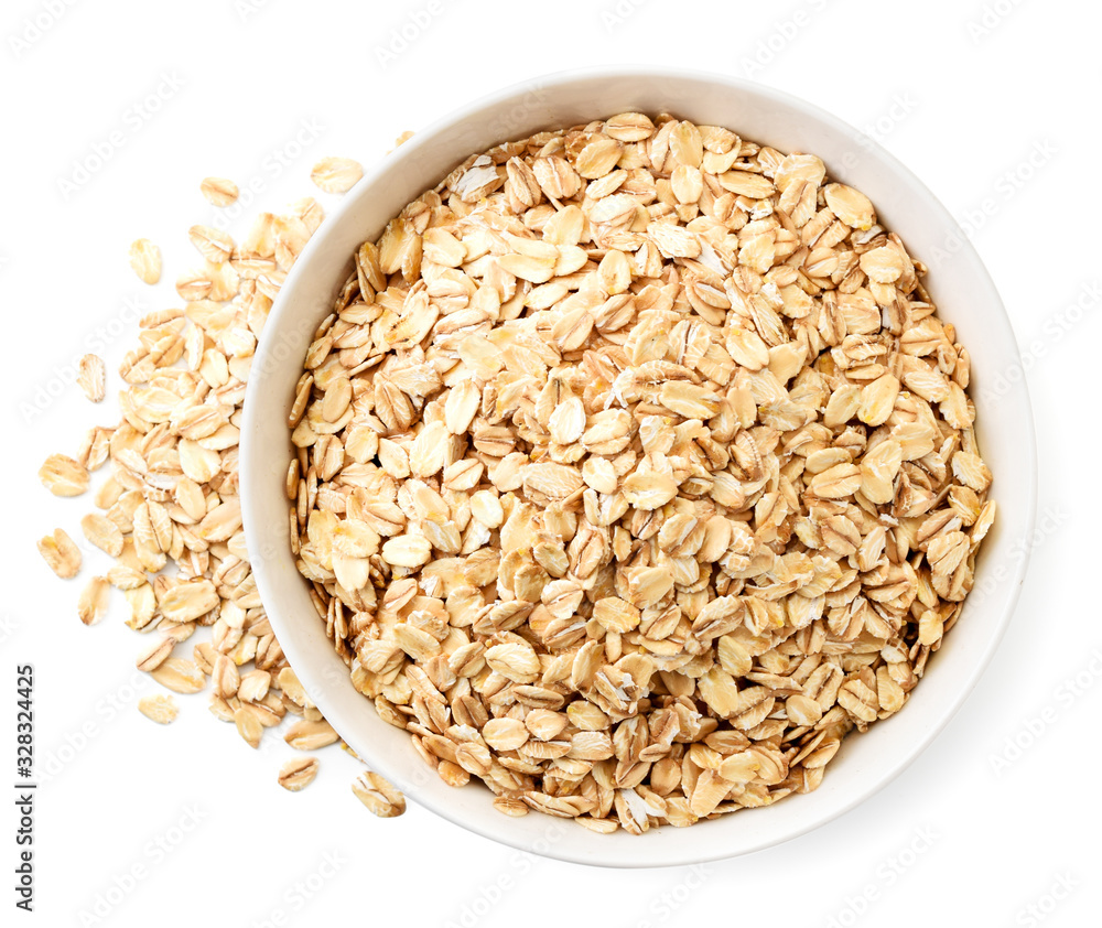 Oatmeal in a plate and scattered on a white background. The view from top Oatmeal in a plate and scattered on a white background. The view from top