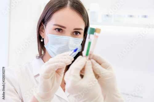 Young pretty female scientist in mask examines a patient s analyzes. Concept of accurate and effective means of preventing and treating viral and age-related diseases. Woman in innovative profession