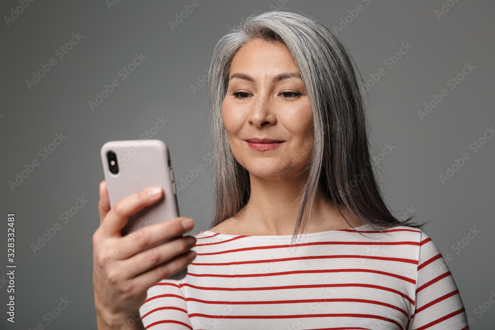 Image of adult mature woman with long white hair holding cellphone Image of adult mature woman with long white hair holding cellphone