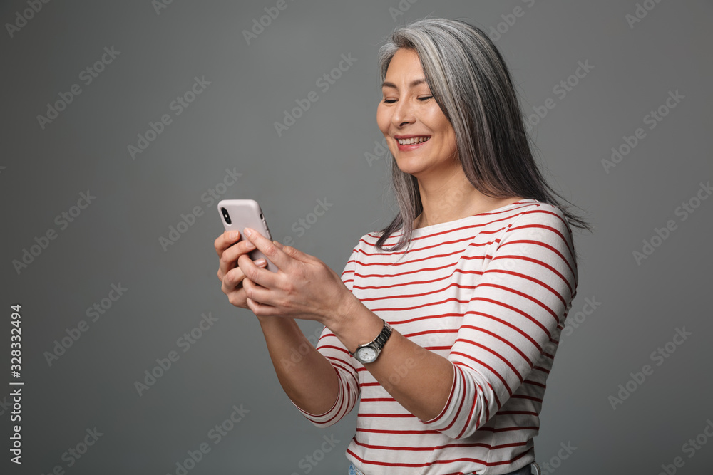 Image of adult mature woman with long white hair holding cellphone Image of adult mature woman with long white hair holding cellphone