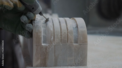 Worker cutting stone plate with professional tools, creates an ornament of the future fireplace