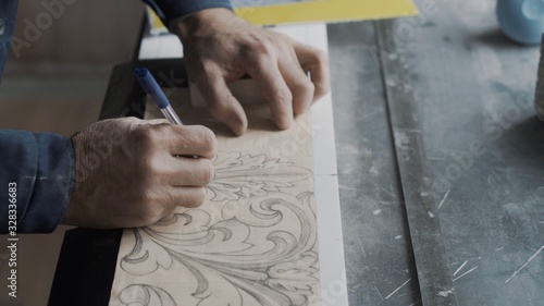 Worker traces lines with a stencil handle on marble plate