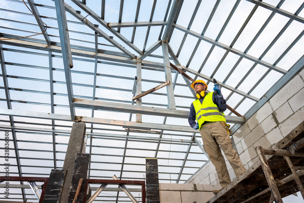 The construction engineer is constructing the steel roof structure of the house. House construction concept. The construction engineer is constructing the steel roof structure of the house. House construction concept.