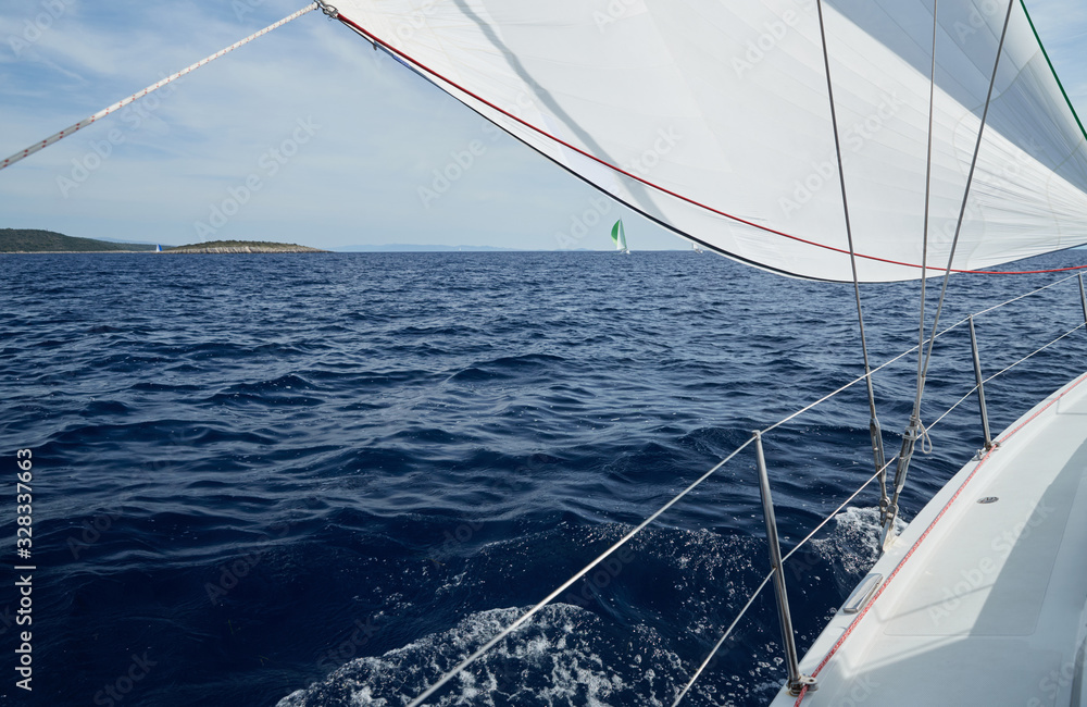 Obraz premium The sailboat goes on sails, a view of the sea and other sailboats through a sail and ropes