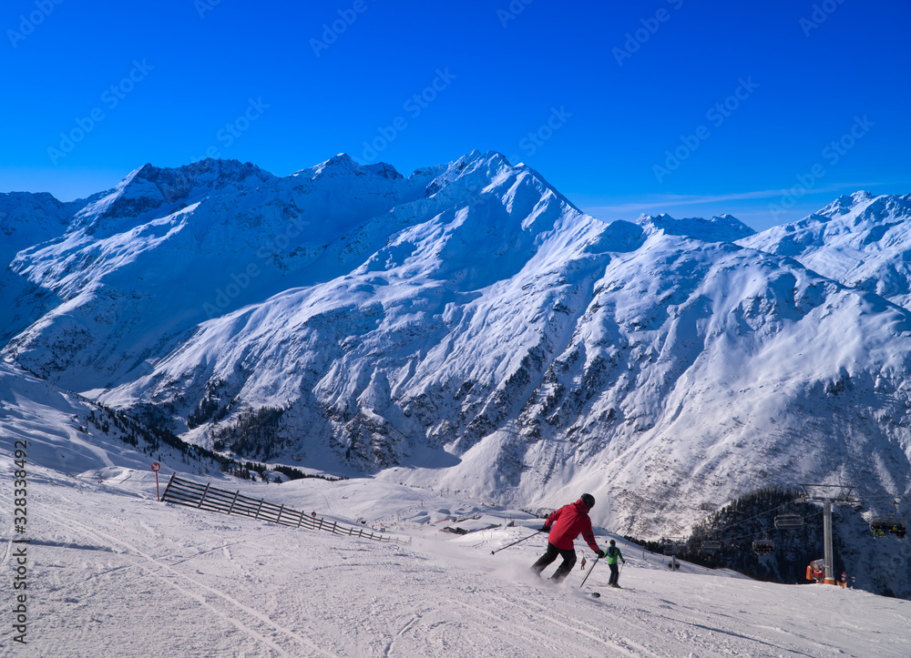 Skiier on slopes on a clear day in St. Anton, Austria - December 2019 - beautiful snowy peaks - winter sports  blue skies