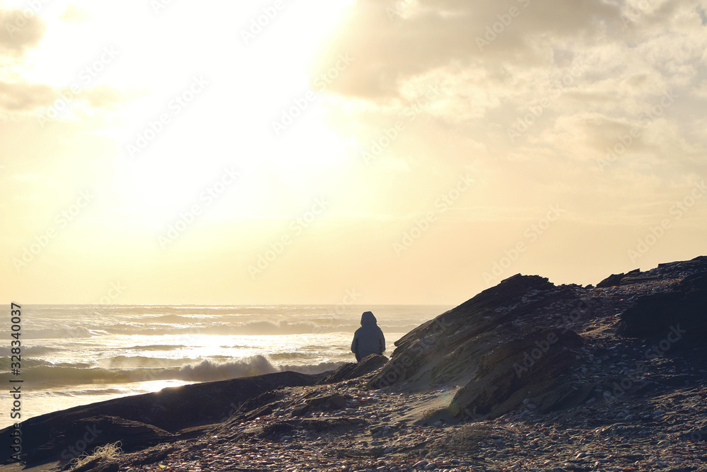 Person sitting and watching an ocean sunset