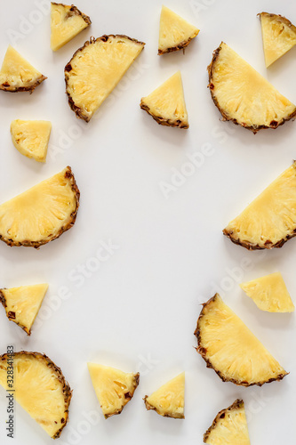 Bright flat lay with pineapple slices on a white background and a copy space in the middle