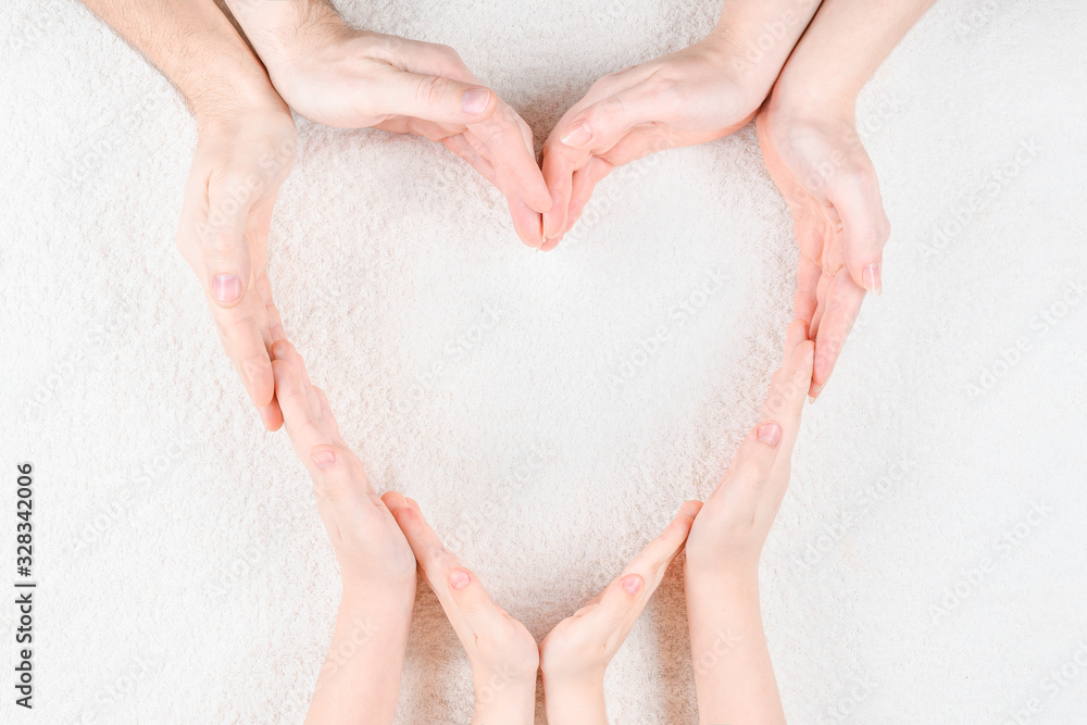 Heart from the hands of parents and children on a white soft fabric. The concept of a large loving family or a symbol of the international family day. Close-up view from above. Heart from the hands of parents and children on a white soft fabric. The concept of a large loving family or a symbol of the international family day. Close-up view from above.