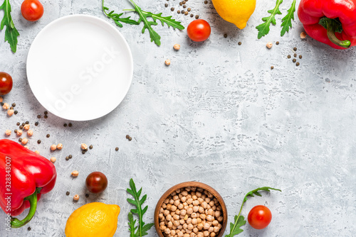 Healthy food. Vegetables, lemon and chickpeas on a concrete background, top view, free space for text. Vegetarian and vegan food concept, copy space. Raw food for cooking Mediterranean cuisine.