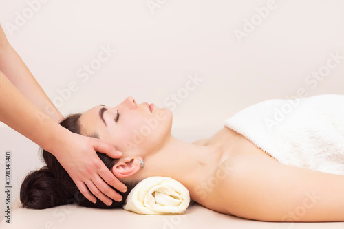 head and temporal massage in a spa salon for a girl. concept of health massage. light background.