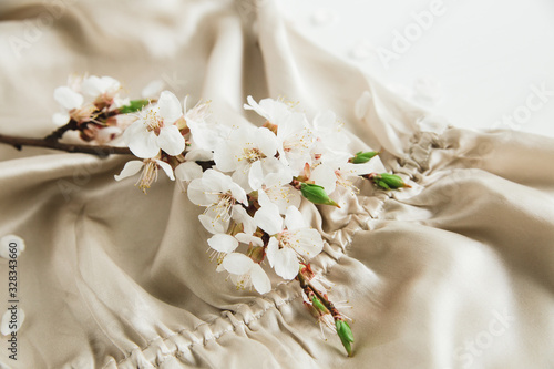 White blossom flowers on the beige silk fabric cloth.Elegant feminine style.White backdrop.