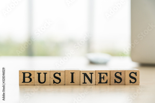 Wording Business alphabet in wooden cube with laptop in the background