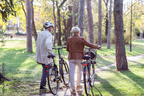 Senior couple with bycicles and helmets in park