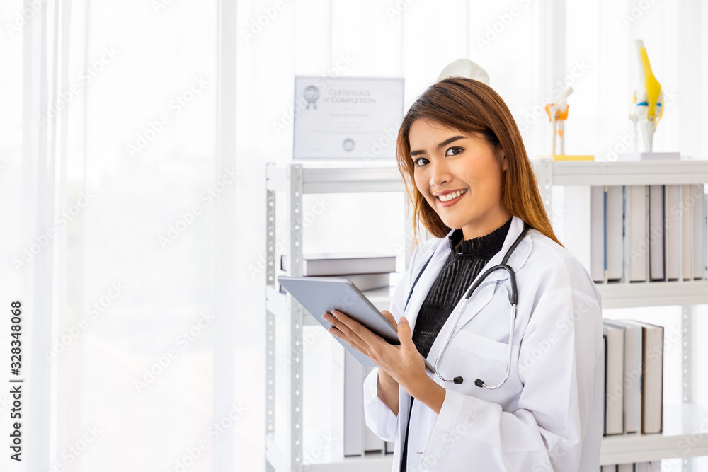 Asian female medical doctor using digital tablet in office clinic hospital with smiling and looking at camera Asian female medical doctor using digital tablet in office clinic hospital with smiling and looking at camera