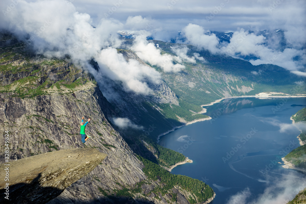 Young man jump on the edge Trolltunga. Norway