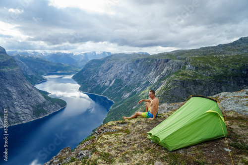 Norwegian fjord landscape with camping tent and young traveller