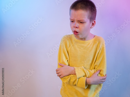 Cute blond boy in yellow sweater in quarantine at home. baby is struggling with illness, fever and strong cough. Epidemic control of coronavirus and proper infection prevention. Child coughs