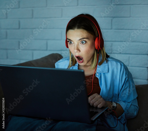 laptop computer headphones movie scared surprised night dark looking girl glowing screen late photo
