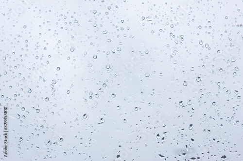 raindrops on glass, closeup, texture of water droplets with a blue tint