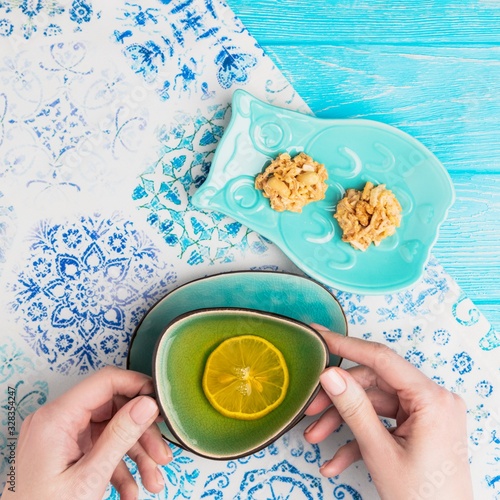 Female hands holding a turquoise cup of lemon tea photo