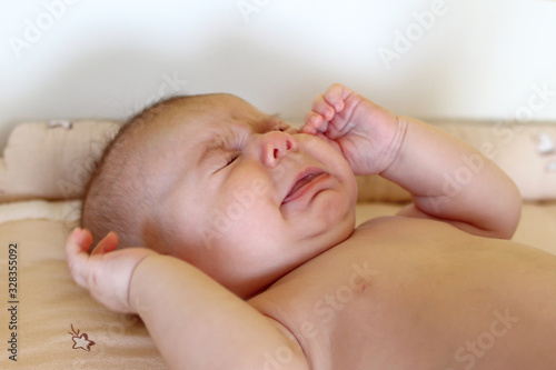 Newborn baby girl is lying on changing table and crying.