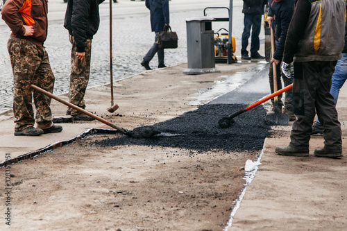 workers in the city smooth fresh asphalt before laying