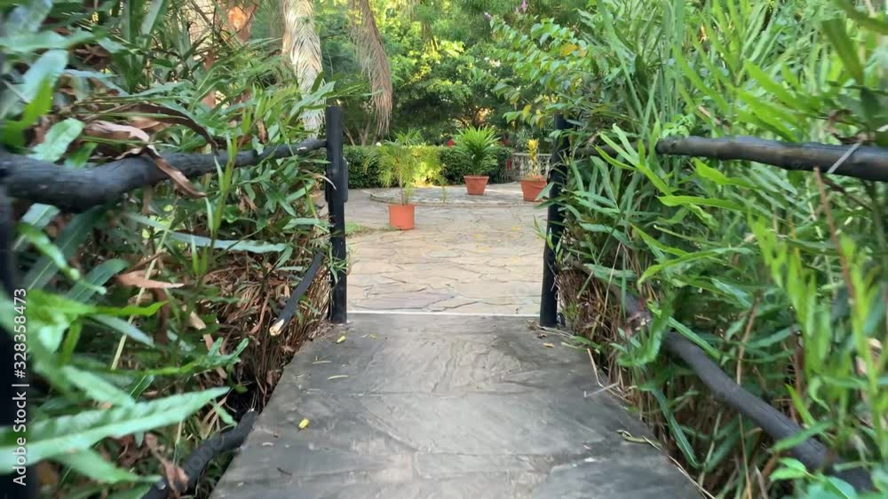 Bridge crossing over small river surrounded by lush green plants. Walk over bridge in resort park grounds. Bridge crossing over small river surrounded by lush green plants. Walk over bridge in resort park grounds.