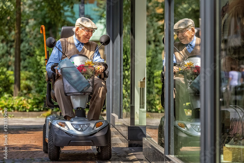 An elderly person on an electric vehicle looks into a shop window
