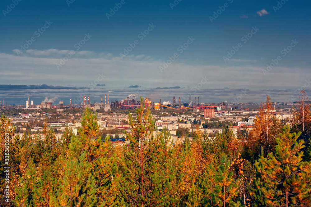 Summer landscape view from high mountain to the autumn forest and urban buildings on the horizon.