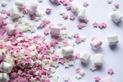 Sugar stars and marshmallows for baking decorations in pink and white colours. White background with copy text space