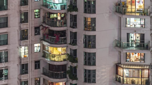 Panning apartment windows in downtown time lapse. Timelapse of residential flats windows lighting up and turning off overnight in Shenzhen, China. Modern life in crowded massive apartment buildings.