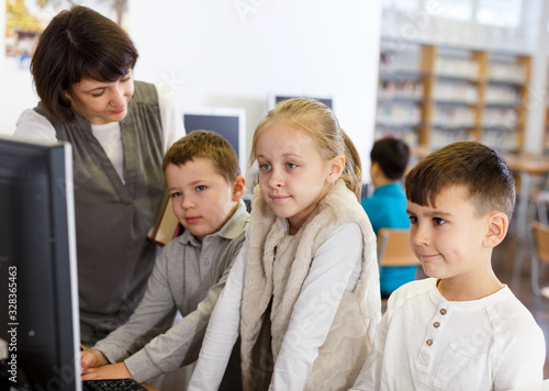 Female teacher giving lesson to kids in computer class