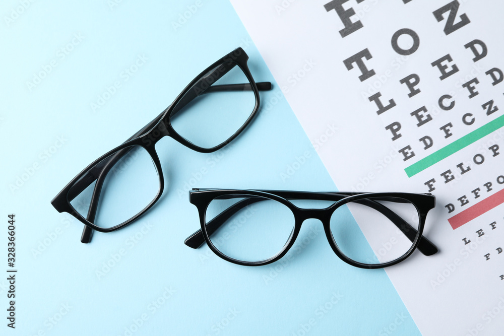 Glasses and eye test chart on blue background, top view Glasses and eye test chart on blue background, top view