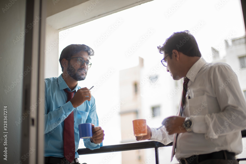 Fototapeta premium Corporate meetings with coffee/tea and cigarette between young and energetic Indian Bengali bosses/officers/managers at balcony of the office building regarding a project. Indian corporate lifestyle