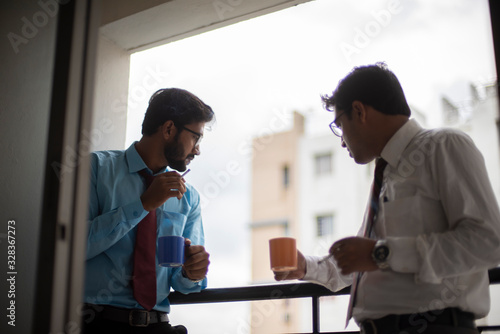 Corporate meetings with coffee/tea  and cigarette between young and energetic Indian Bengali bosses/officers/managers at balcony of the office building regarding a project. Indian corporate lifestyle