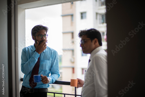 Corporate meetings with coffee/tea between young and energetic Indian Bengali bosses/officers/managers and secretary at balcony of the office building regarding a project. Indian corporate lifestyle