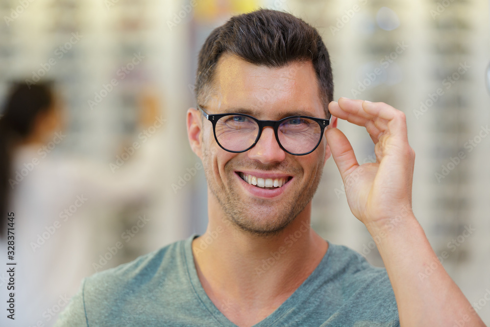 handsome man choosing glasses in optics store handsome man choosing glasses in optics store