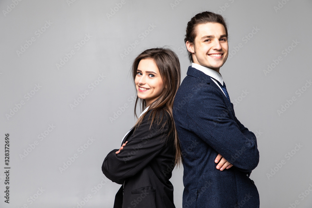 Two young business people standing back to back with hands crossed isolated on grey background