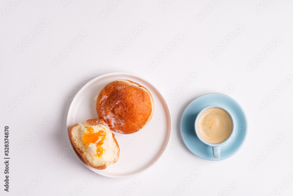 Homemade baked donut on a white ceramic plate and cup of coffee on a light grey background. Flat lay. Homemade baked donut on a white ceramic plate and cup of coffee on a light grey background. Flat lay.