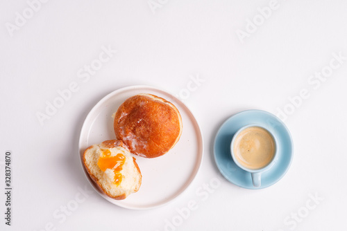 Homemade baked donut on a white ceramic plate and cup of coffee on a light grey background. Flat lay.